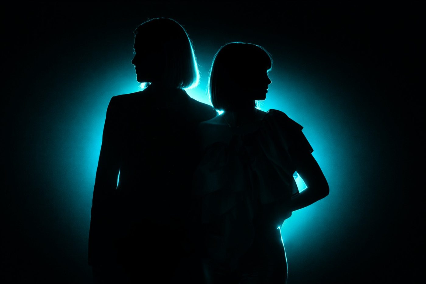 The two founders of Endgame Strategy Lab standing back to back, silhouetted against a cyan light.
